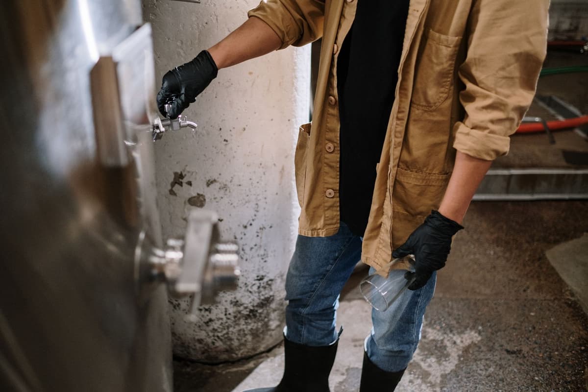 factory worker tapping stainless steel pipe with wrench