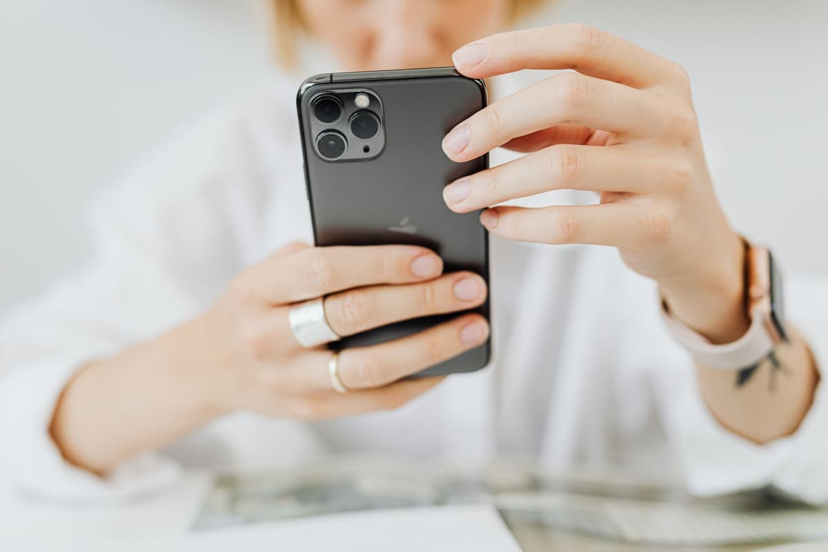 a person holding an iPhone up to a single blueberry on a pedestal