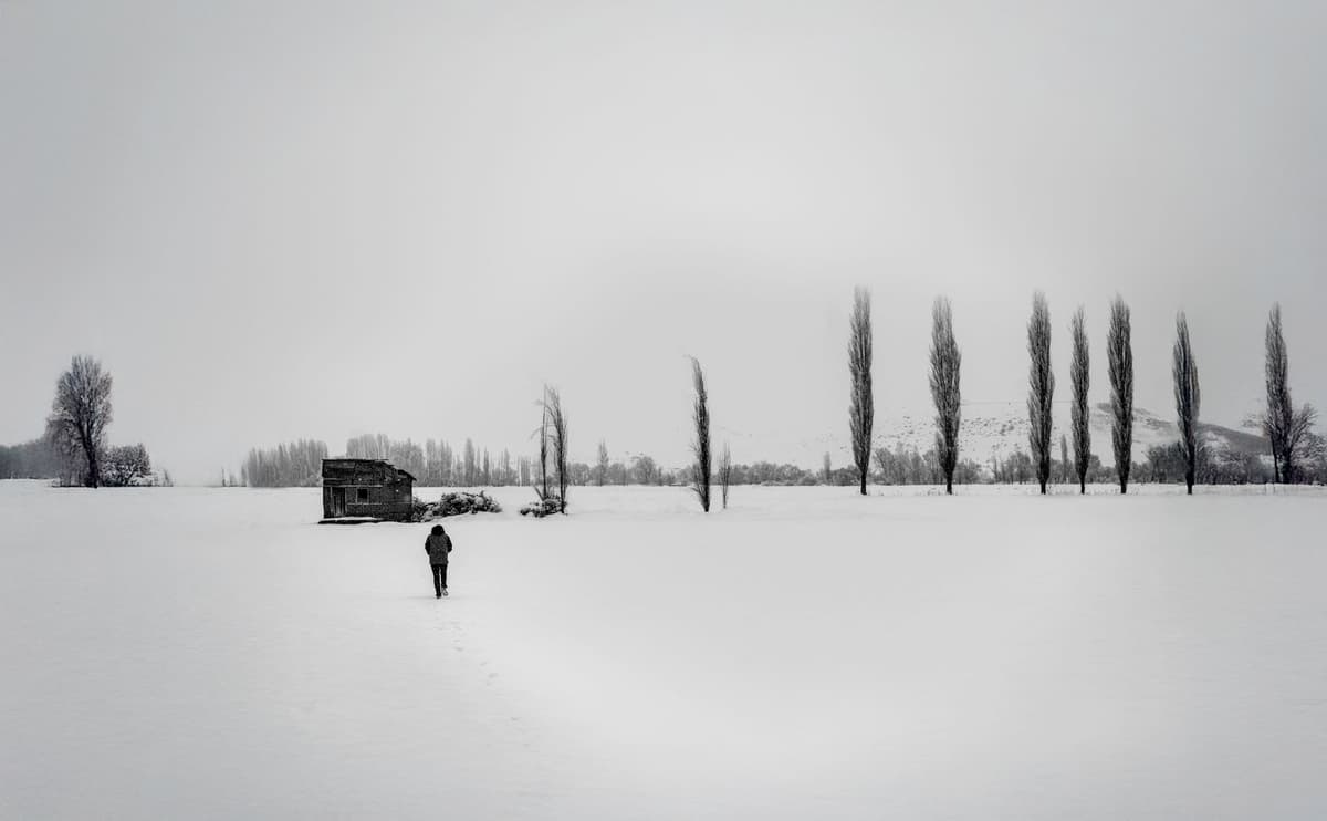 a lone tractor in a vast snowy field under grey skies