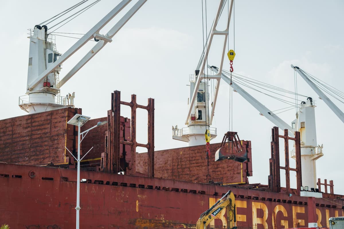 a massive white rigid sail towering over a steel cargo ship deck