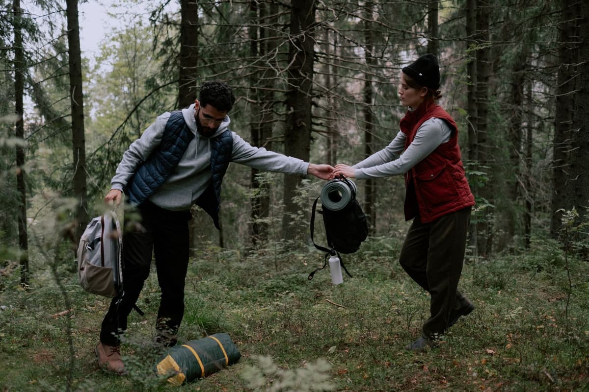 a person struggling to carry a bulky piece of medical equipment through a dense forest