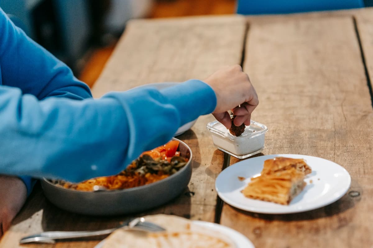 a man in a tuxedo eating a burrito at a folding table