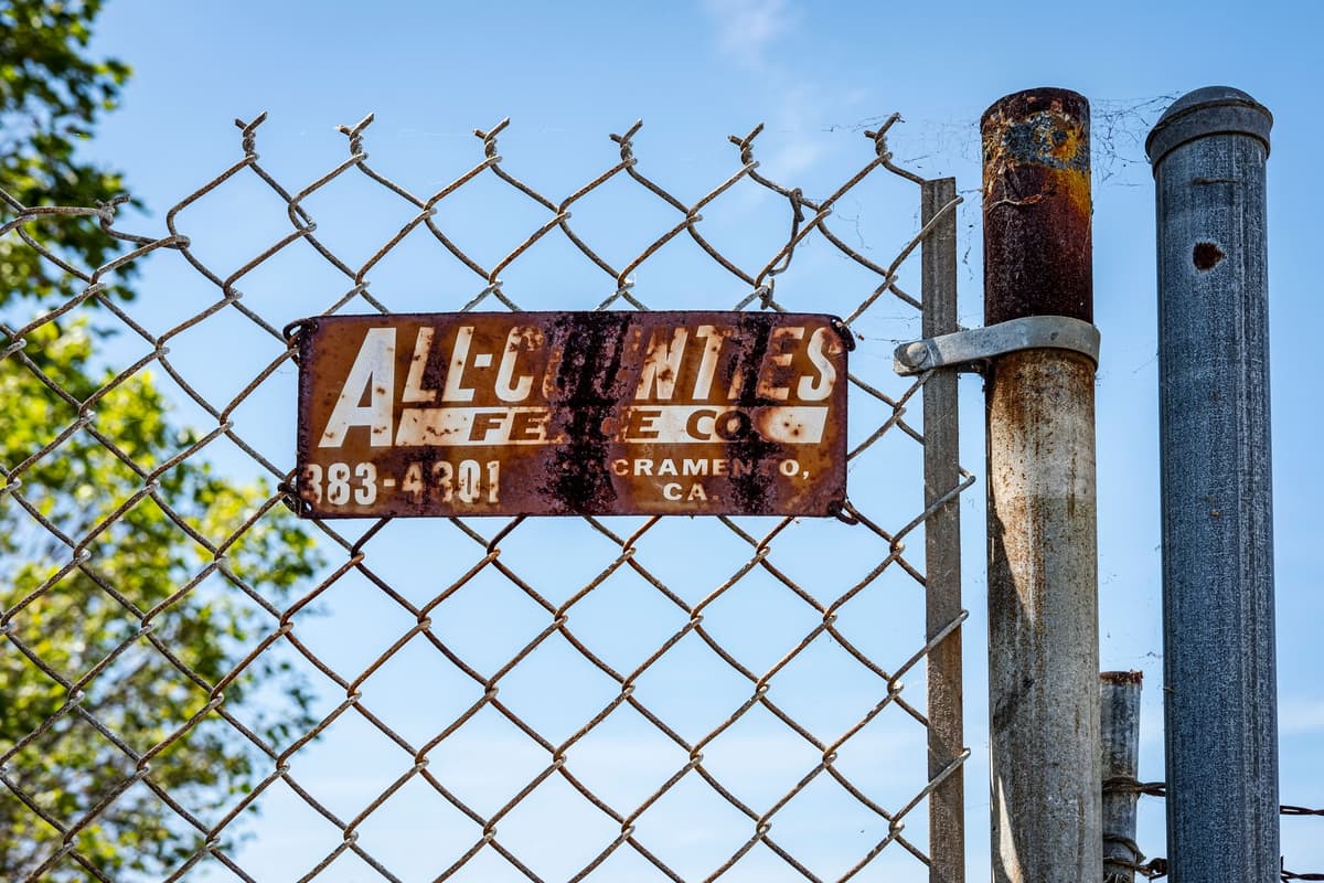 a rusted metal fence cutting through tall prairie grass