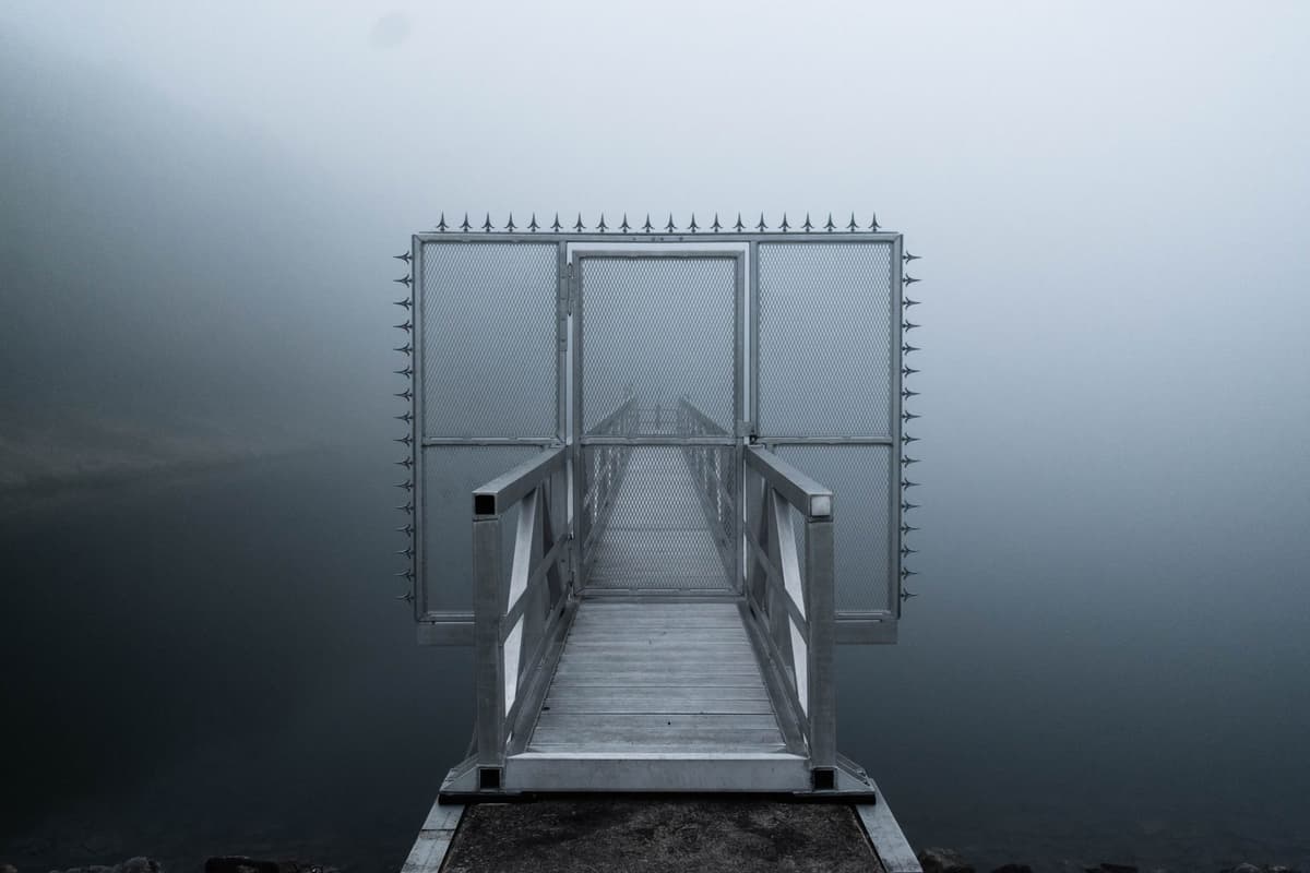 a rusted iron gate partially submerged in murky lake water
