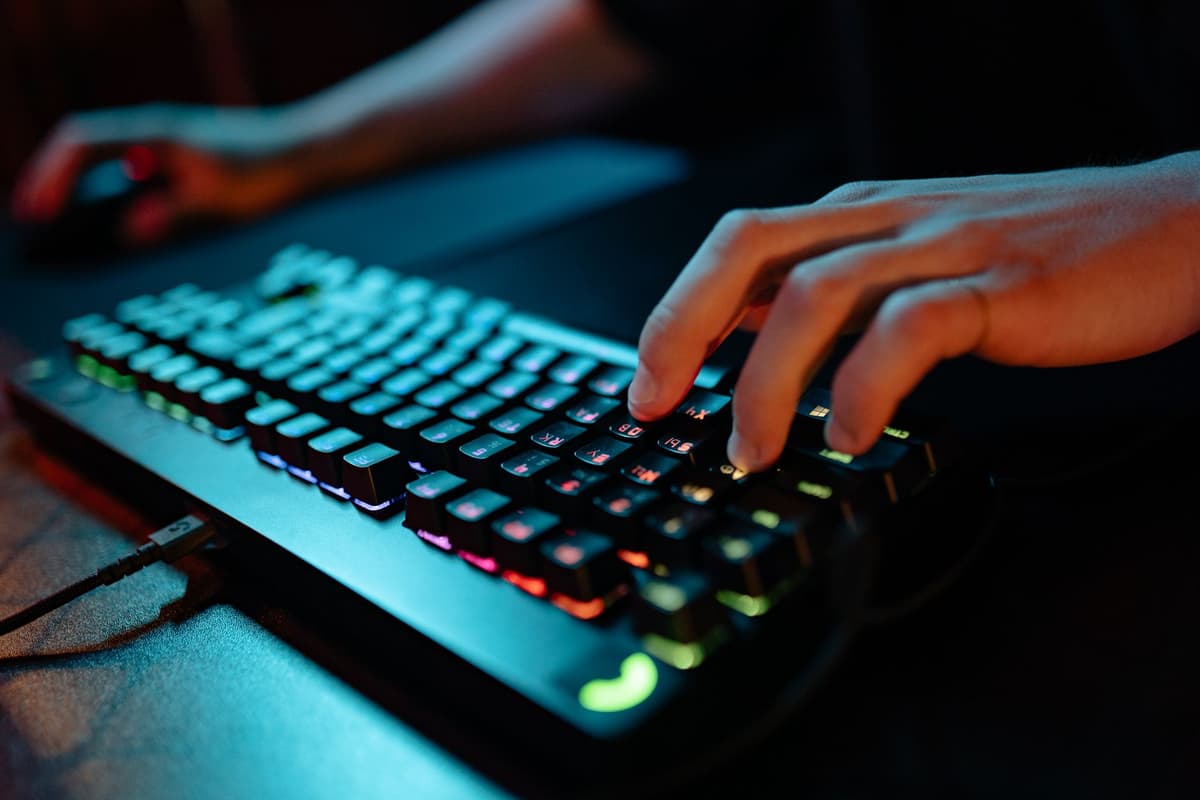 bruised hands over an illuminated mechanical computer keyboard