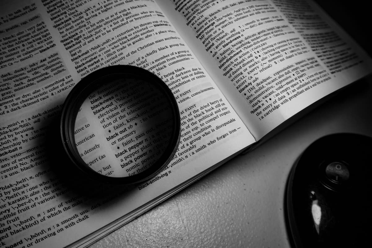 a dusty leather-bound dictionary with a magnifying glass