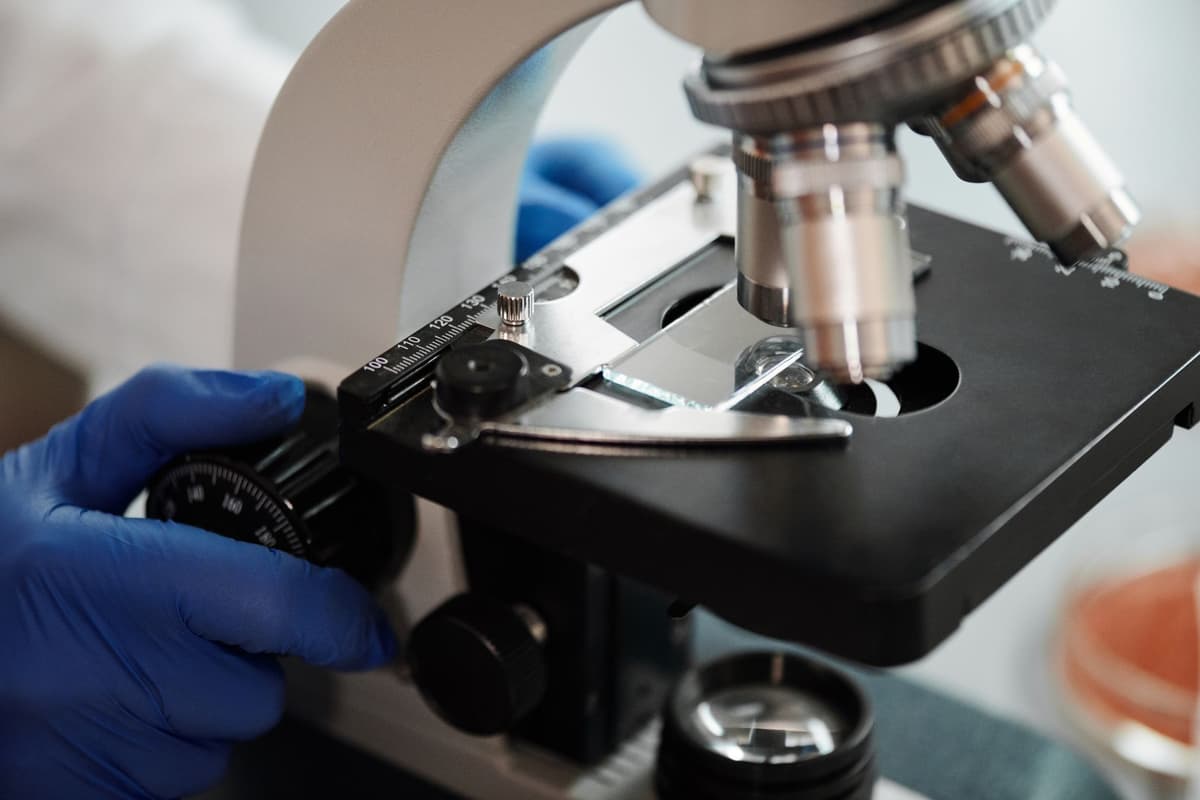 a single glowing cell under a high-powered microscope lens