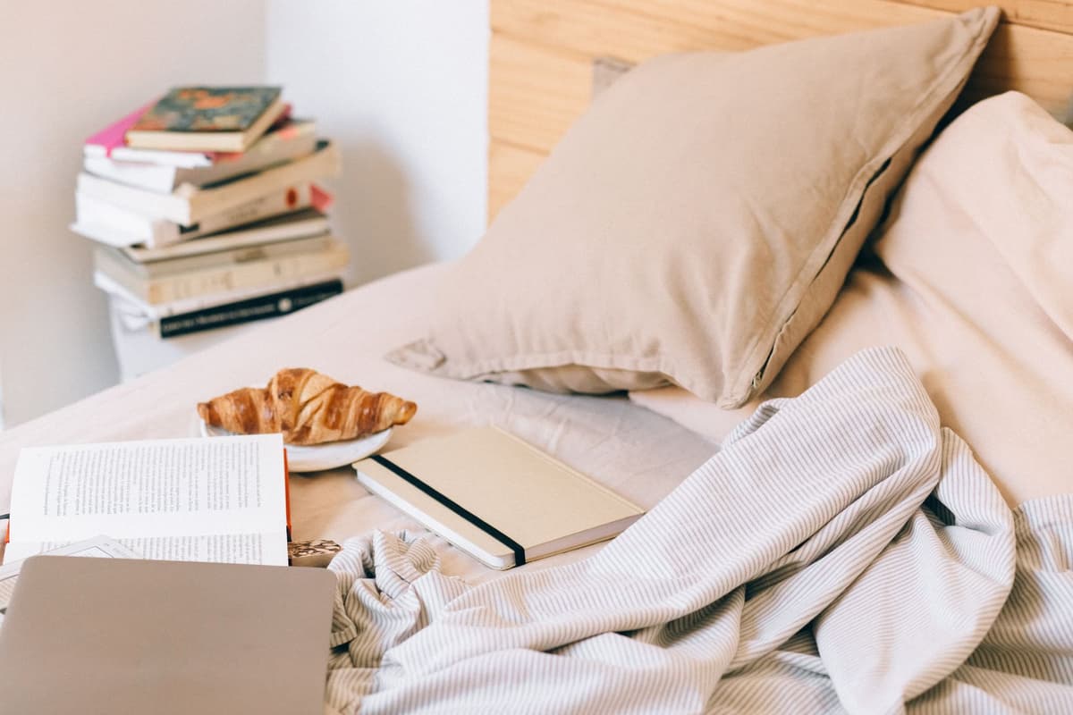 glowing laptop open on unmade messy bed at night