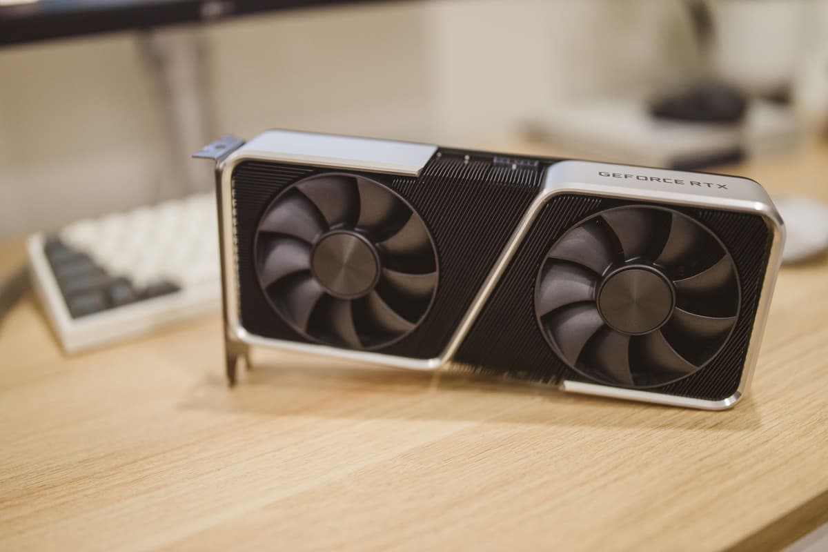 a high-end graphics card resting on a wooden desk near an easel