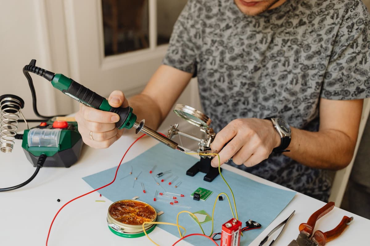 a person using a magnifying glass and soldering iron on a circuit board next to a toaster