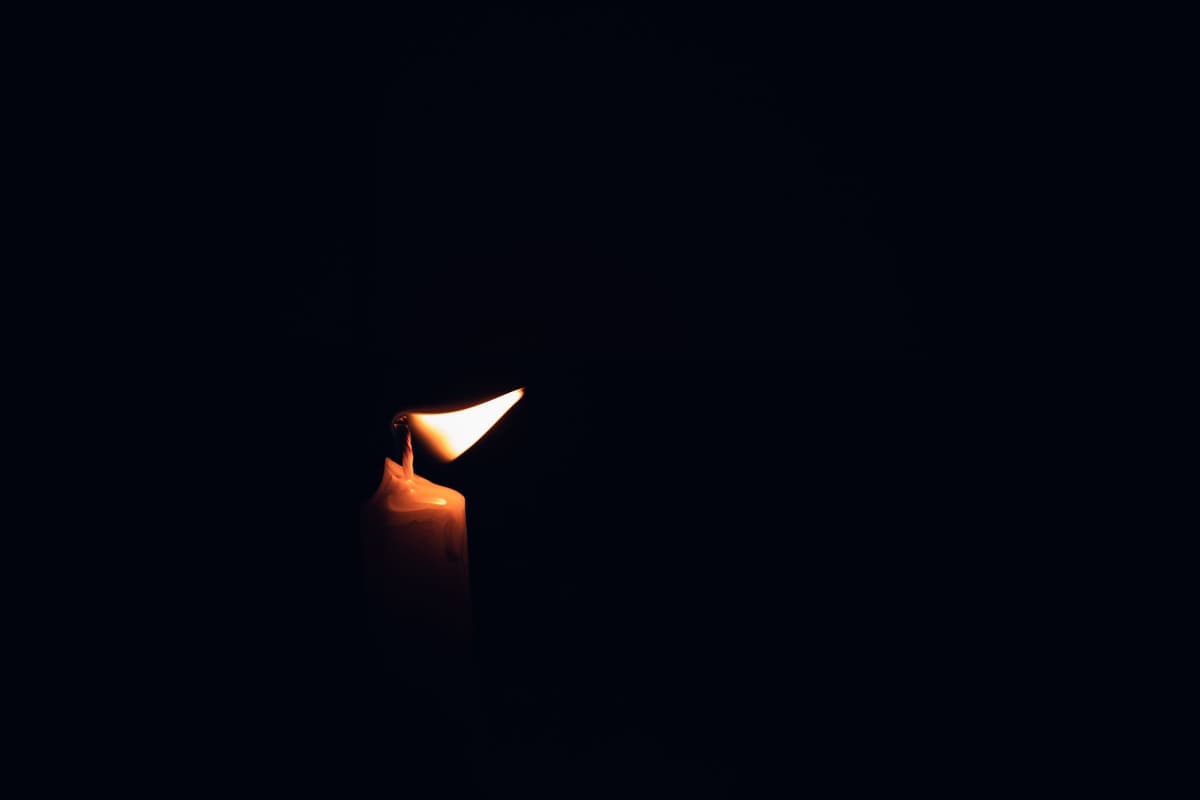a single lit candle on a dark wooden desk