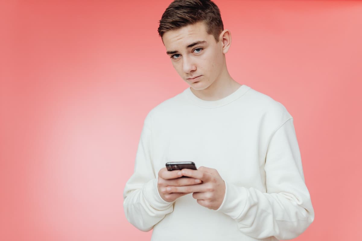 a confused teenager staring at a brick wall while holding a phone