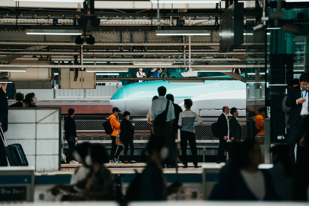 a crowded Japanese train platform with digital displays