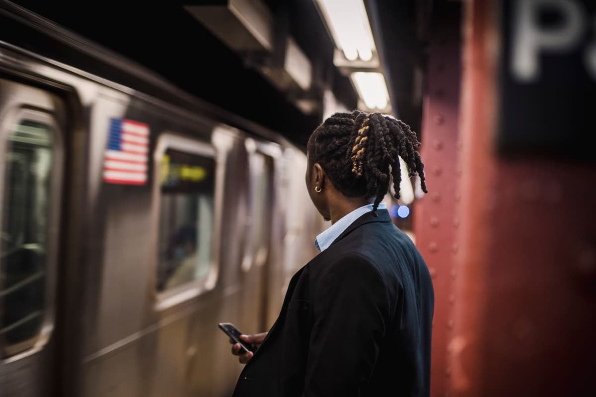 a person staring at a glowing smartphone in a dark subway station