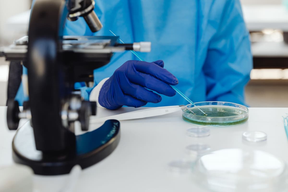 a sterile laboratory bench with a glowing laptop screen next to an unused microscope