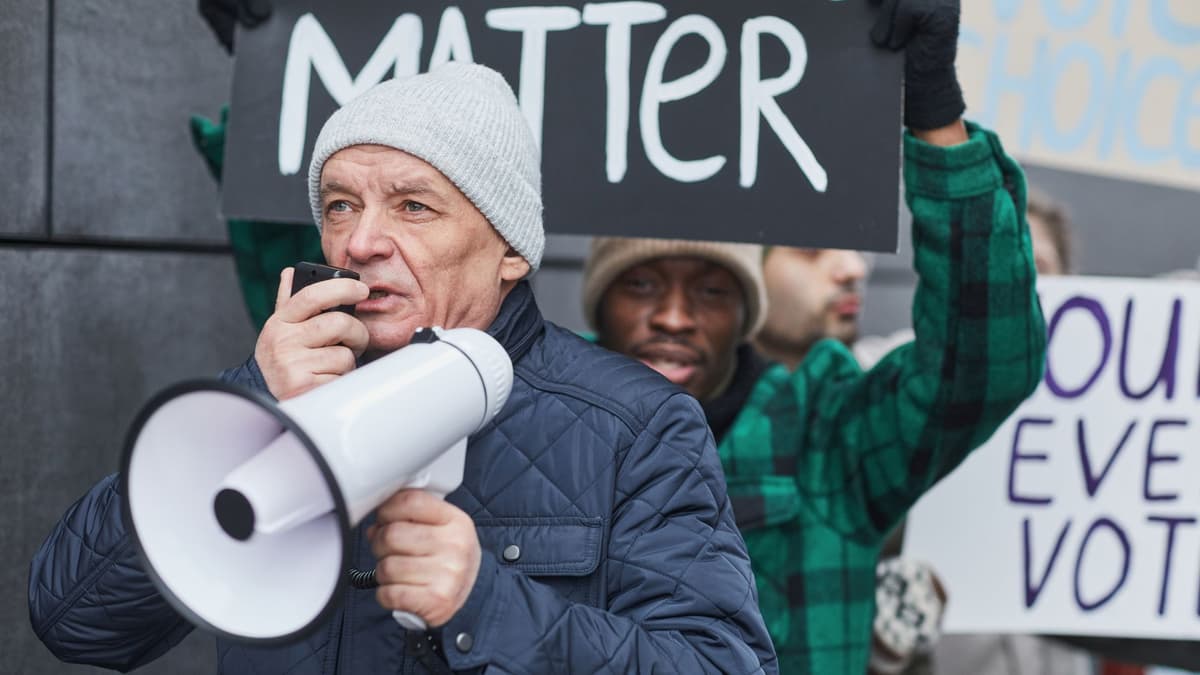 a woman wearing a black turtleneck holding a megaphone