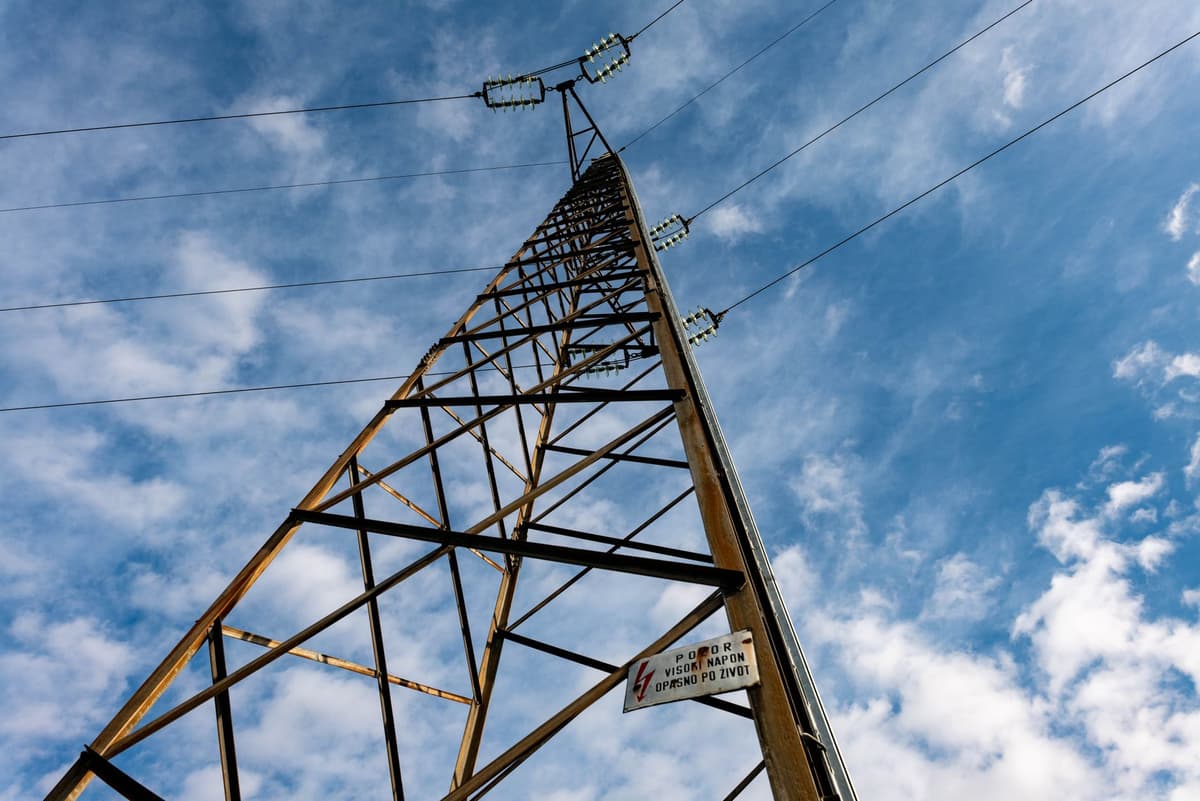 a high-voltage power line tower collapsing into snow