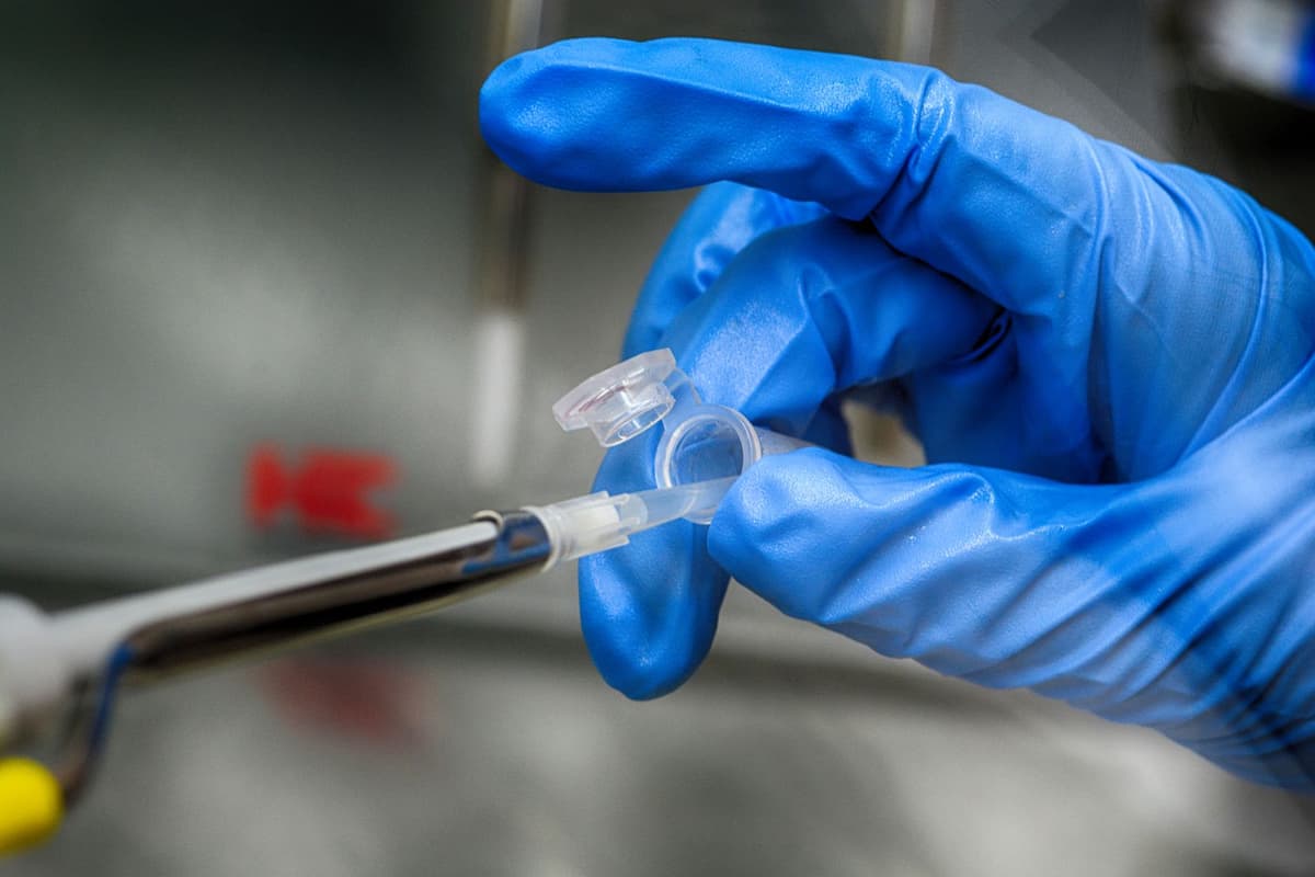 a high-tech laboratory pipette dropping liquid into a vial