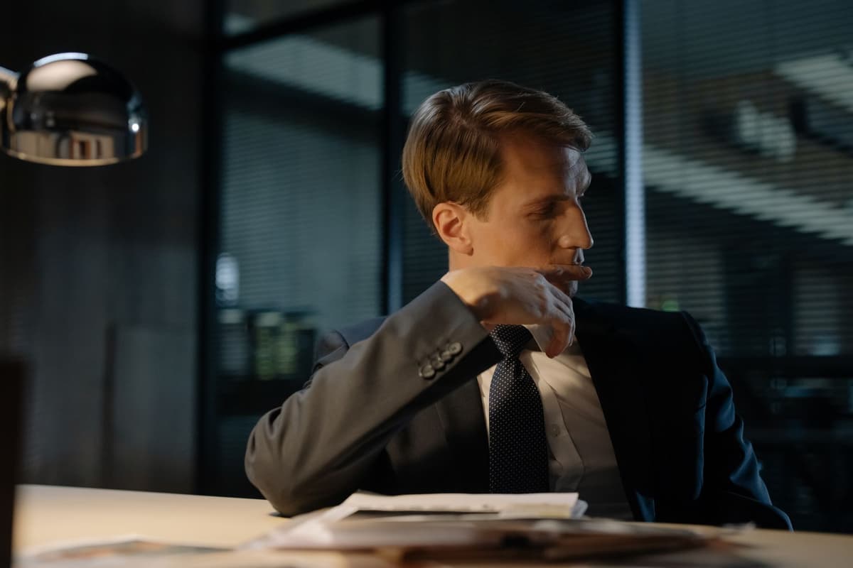 a person in a suit sweating while looking at a complex spreadsheet with red numbers