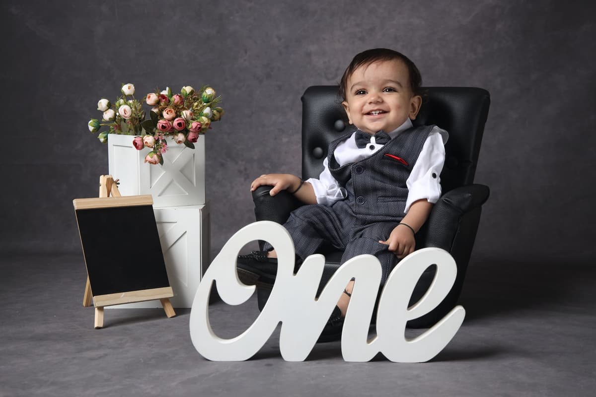 a toddler in a business suit holding a juice box