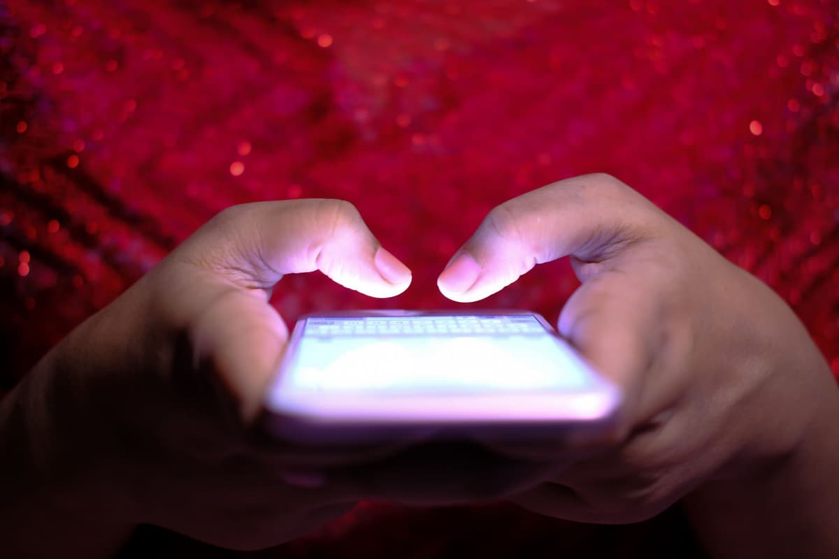 a person squinting at a glowing smartphone screen covered in overlapping popups