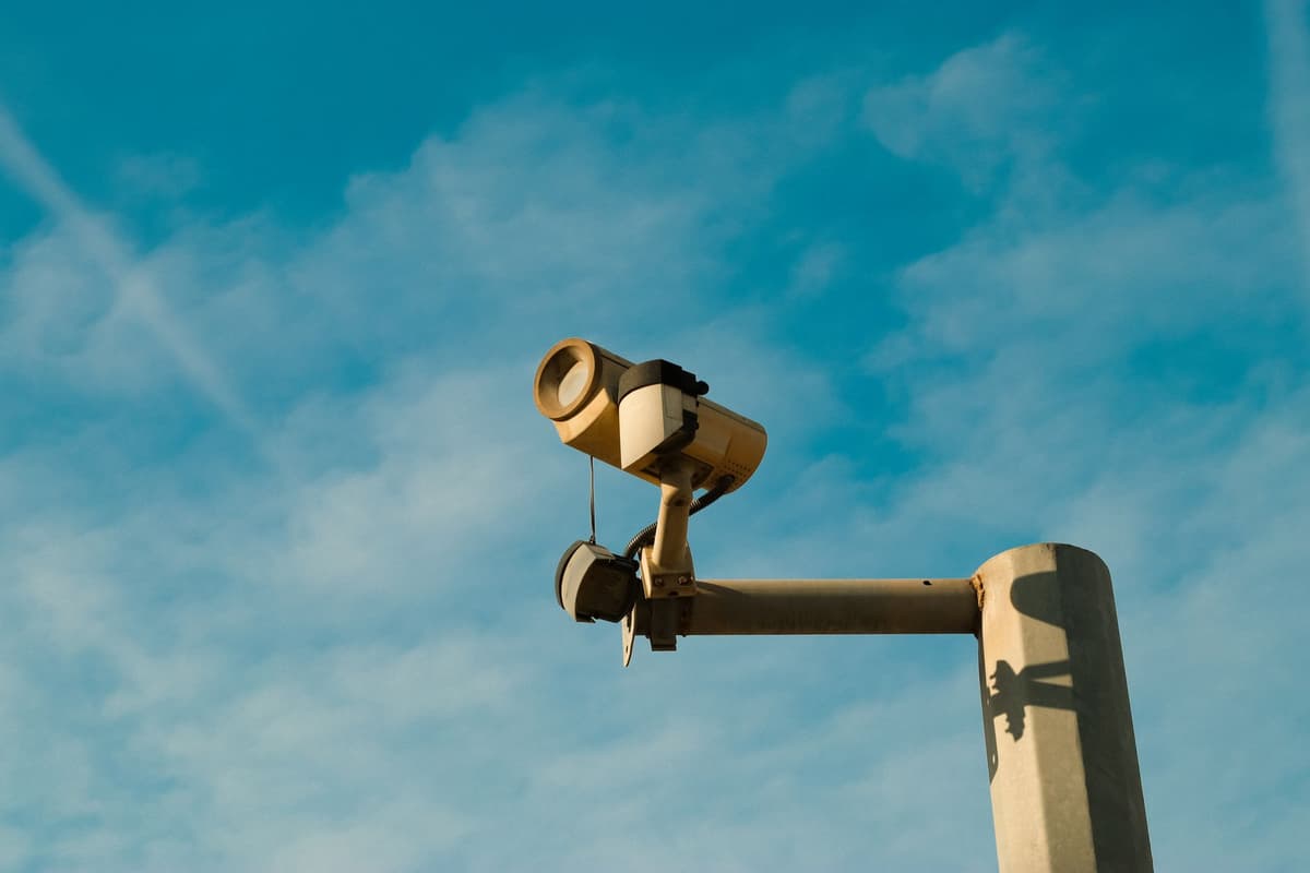 black surveillance camera mounted on wooden utility pole