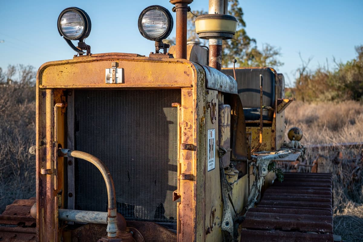 a rusty tractor pulling up rows of vines