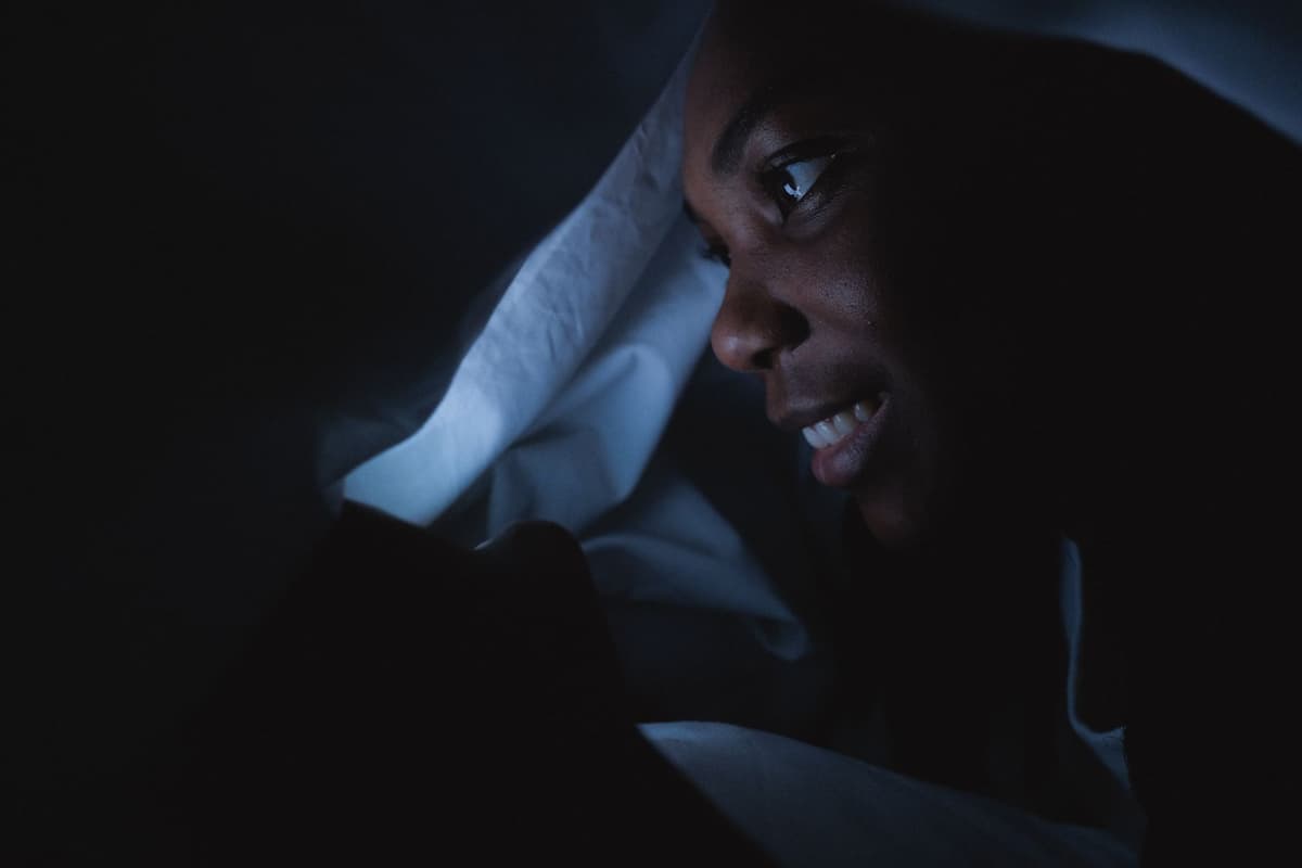 a single glowing smartphone in a dark bedroom