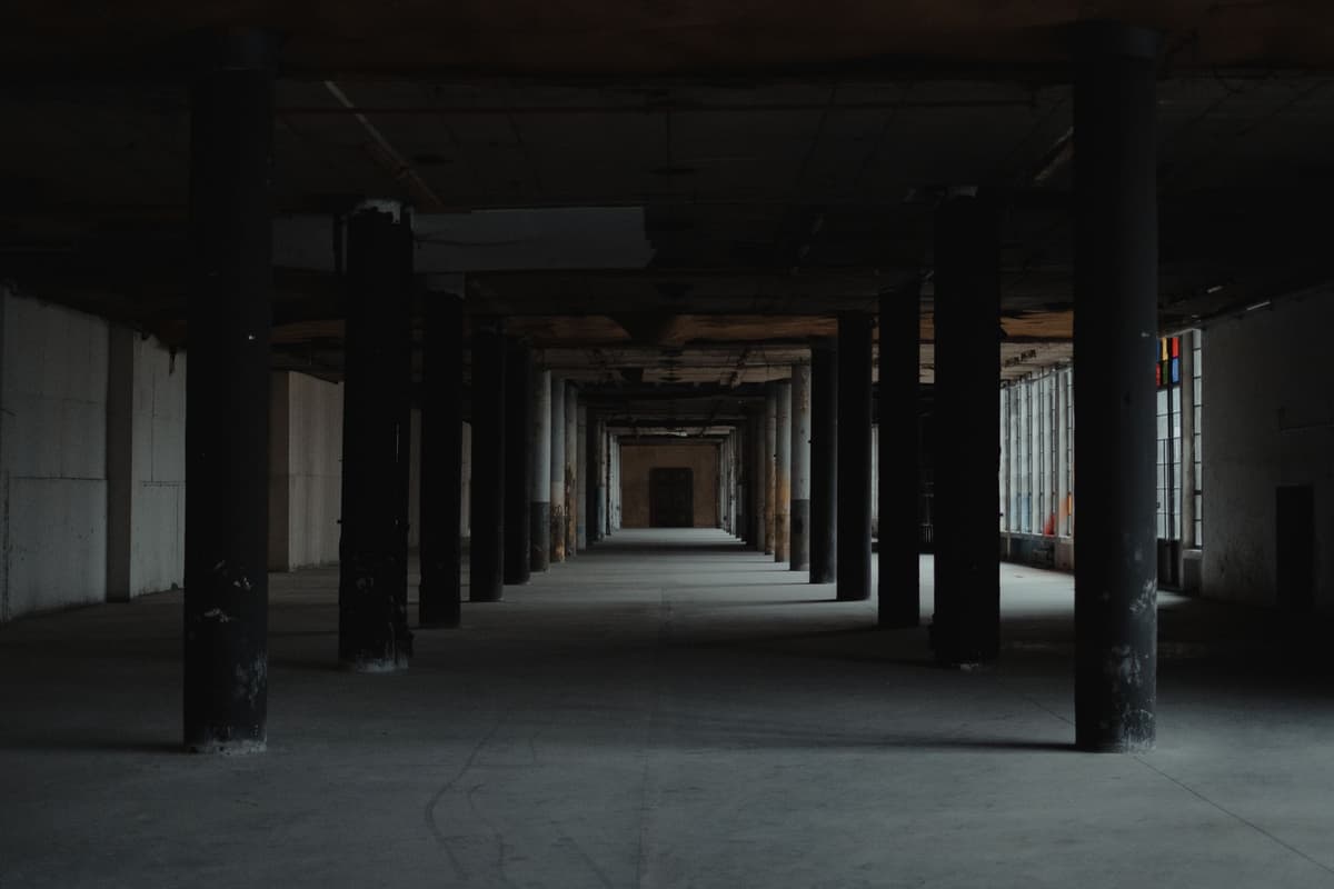 a single gold coin sitting inside a massive empty warehouse
